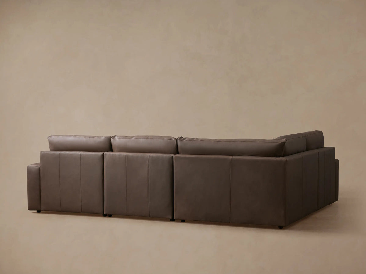 Close-up of a Kipton Wide Arm Leather Sectional with rich brown leather, wide armrest, and a motion control button.