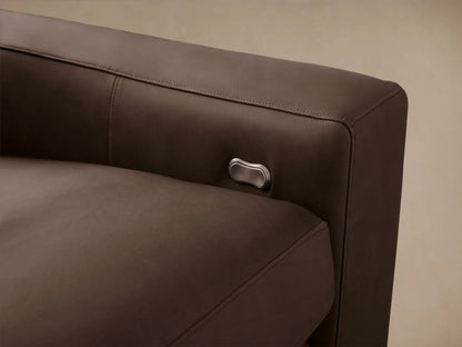 Kipton 3-piece modular motion sofa in rich taupe leather, wide arms, against a beige wall & wood floor.
