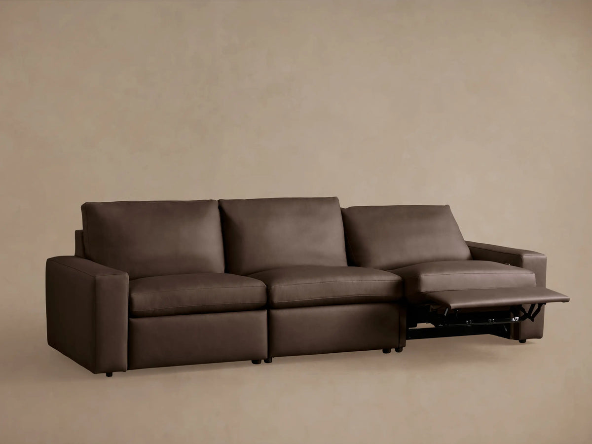 Kipton wide-arm 3-piece dark brown leather motion sofa with two footrests extended, shown against a neutral wall.