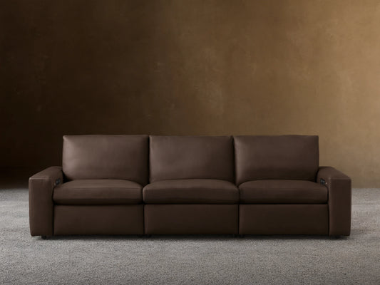 Kipton Wide-Arm Leather Three-Piece Motion Modular Sofa in rich dark brown, with plump cushions, on a wood floor.