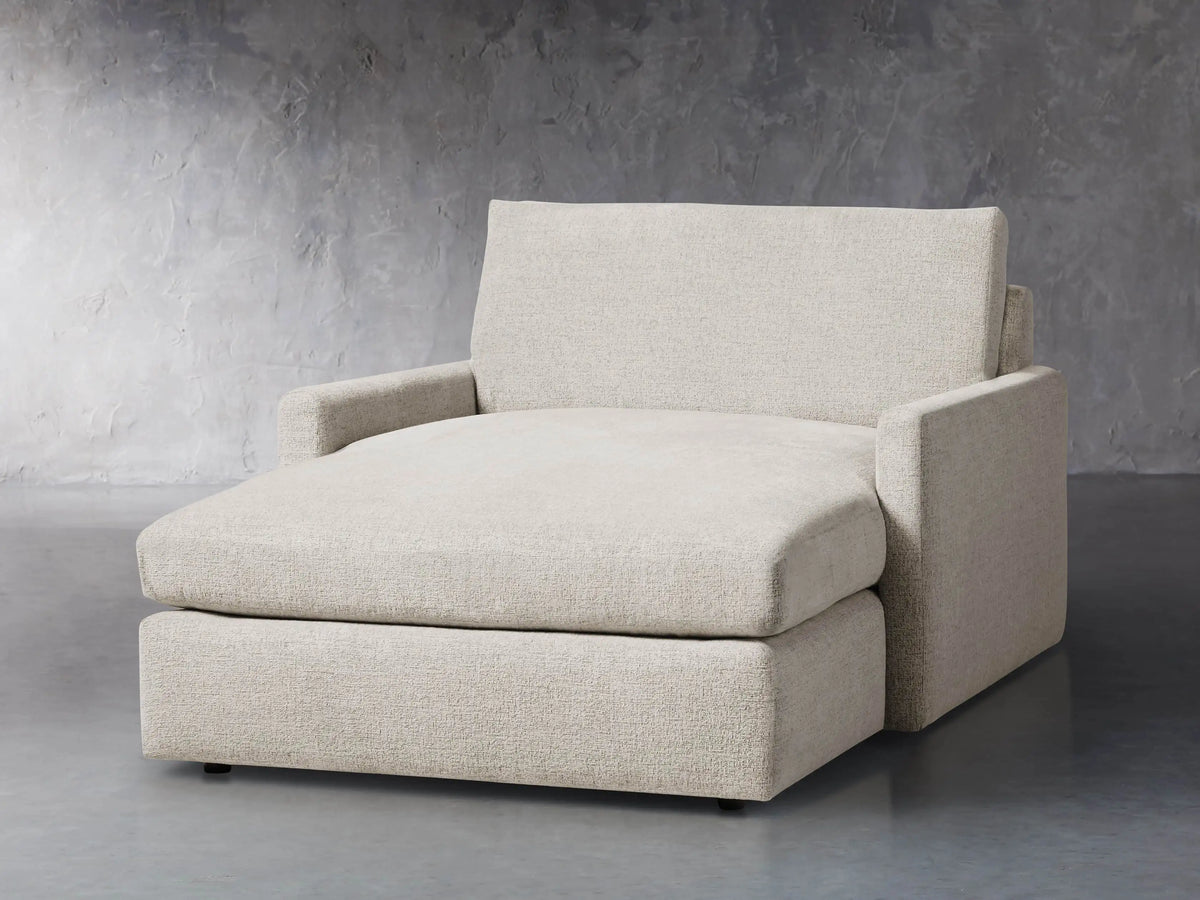 Front view of a light beige Kipton Slim Two Arm Chaise, featuring textured fabric, low arms, and an extended chaise seat.