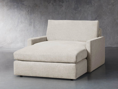 Front view of a light beige Kipton Slim Two Arm Chaise, featuring textured fabric, low arms, and an extended chaise seat.