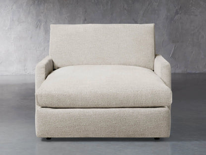 Front view of a light beige Kipton Slim Two Arm Chaise, featuring textured fabric, low arms, and an extended chaise seat.