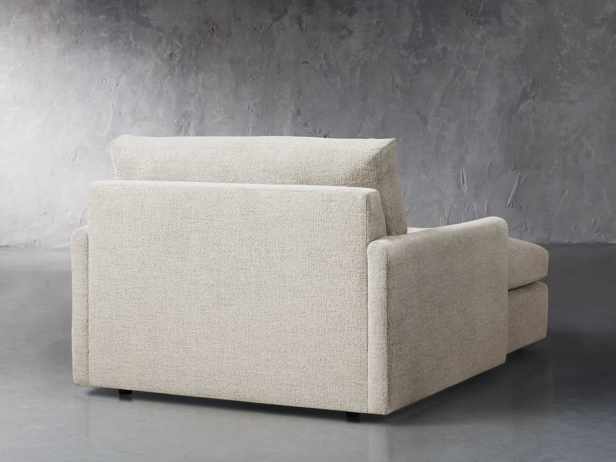 Side profile of a light beige Kipton Slim Two Arm Chaise upholstered in textured fabric, with a deep seat and extended footrest.