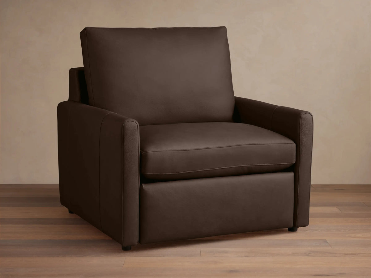 A dark brown Kipton Leather Motion Recliner with a sleek design. Features smooth leather, slim arms, and cushioned backrest on a wooden floor.