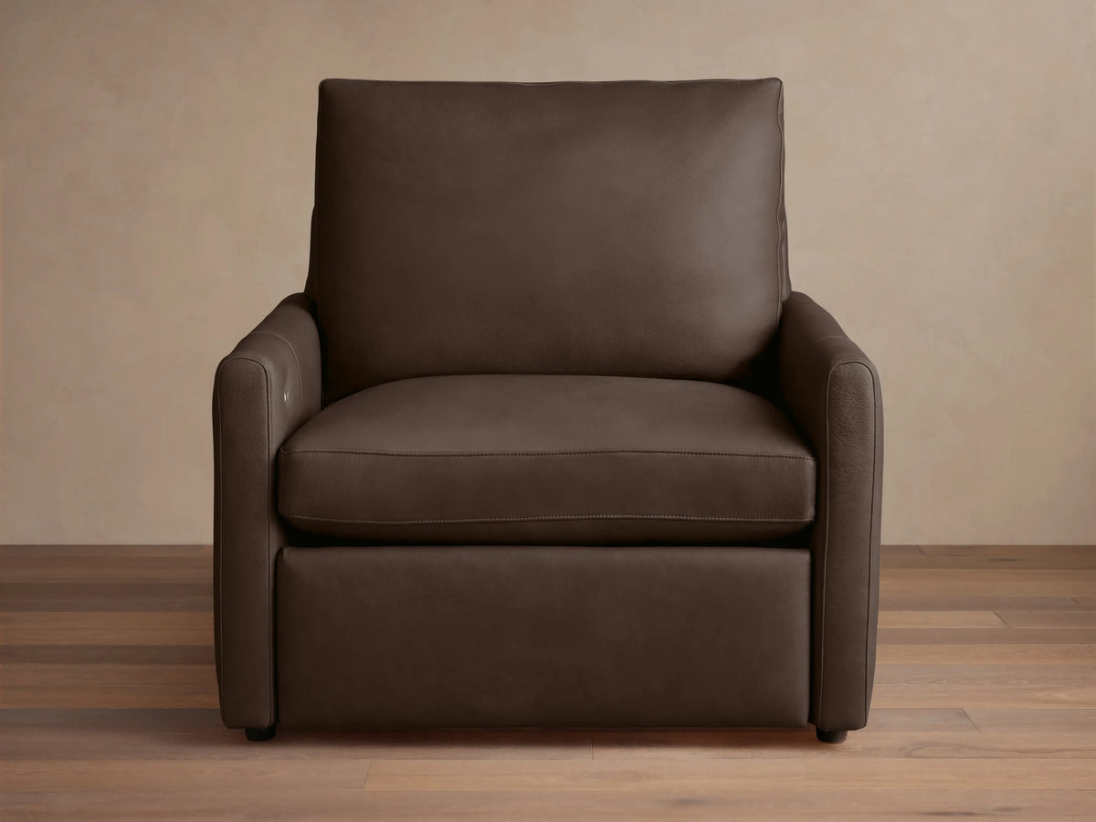 A dark brown Kipton Leather Motion Recliner with a sleek design. Features smooth leather, slim arms, and cushioned backrest on a wooden floor.