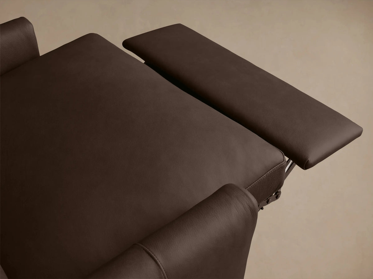Close-up view of Kipton Leather Motion Recliner armrest, showcasing a smooth brown leather finish and a sleek silver oval control button.