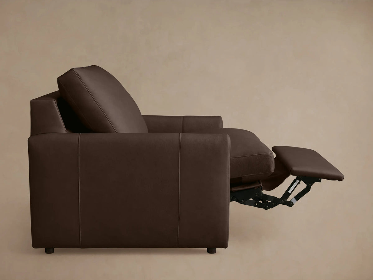 Brown leather recliner partially reclined, showing cushioned seat, extended footrest, and slim armrests, viewed from above.