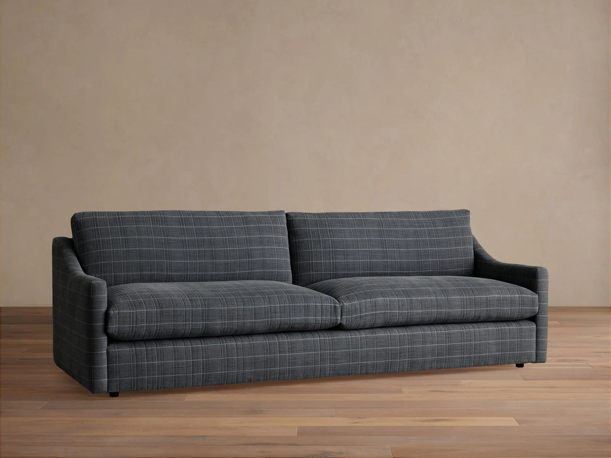 Front view of the grey plaid Kipton Slope Arm Sofa, featuring slope arms, styled with textured pillows and a throw blanket.