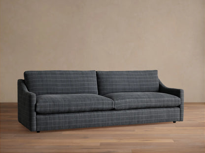 Front view of the gray plaid Kipton Slope Arm Sofa with decorative pillows and a brown throw blanket in a living room.