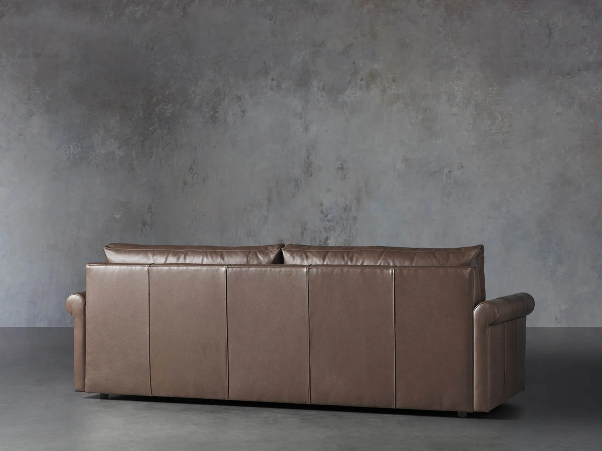 Close-up of the brown Kipton Leather Rolled Arm Sofa, highlighting the rolled right arm and cushion with light piping detail.