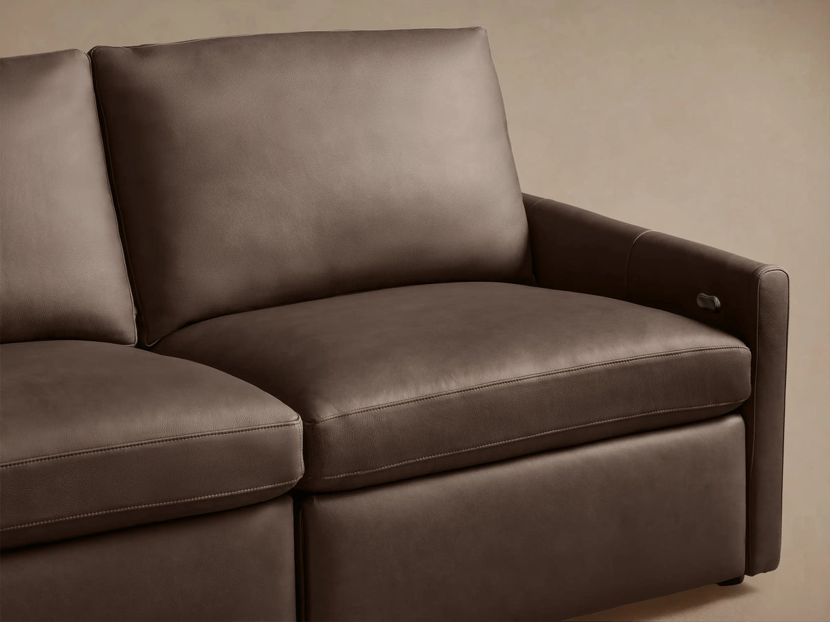 Dark brown Kipton Leather Three-Piece Motion Modular Sofa with slim arms, button controls on side. Set on light hardwood floor.