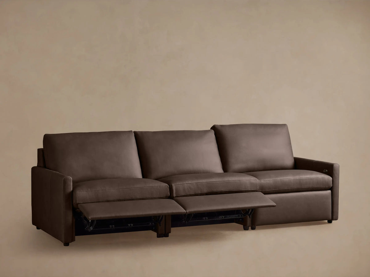 The Kipton Leather Three-Piece Motion Modular Sofa, shown from the back, features dark brown leather upholstery and slim arms, with three distinct sections.