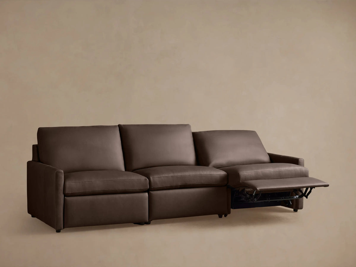 Brown leather Kipton three-piece modular sofa on taupe background, two seats reclined. Slim arm design with plush cushions.