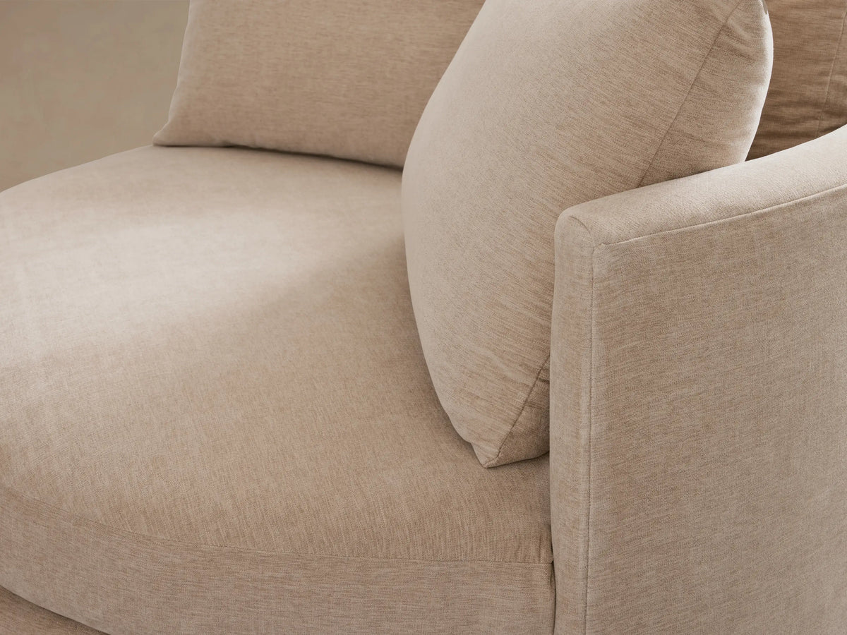 Kipton Oversized Swivel Chair in beige, featuring a round design with two large back cushions, on a wooden floor.