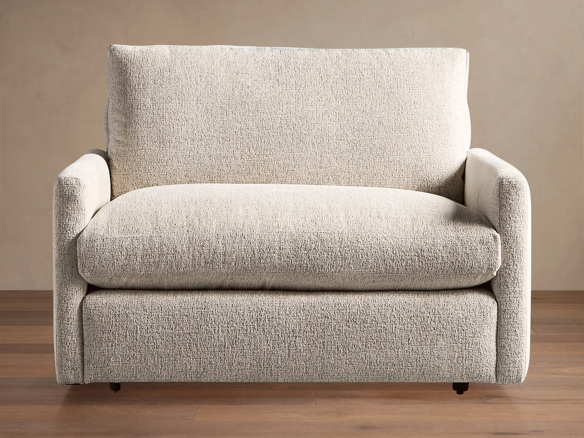 Kipton Slim Arm Chair, front view, upholstered in light beige textured fabric with slim arms, large back & seat cushions.