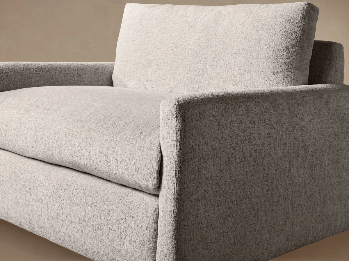 Kipton Slim Arm Chair, front view, upholstered in light beige textured fabric with slim arms, large back & seat cushions.