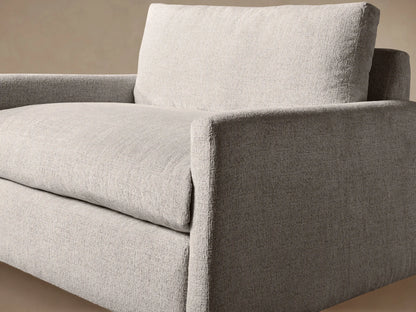 Kipton Slim Arm Chair, front view, upholstered in light beige textured fabric with slim arms, large back & seat cushions.