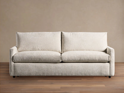 Off-white Kipton Slim Arm Sleeper Sofa with textured fabric, two seat cushions, two back cushions, on a wood floor.