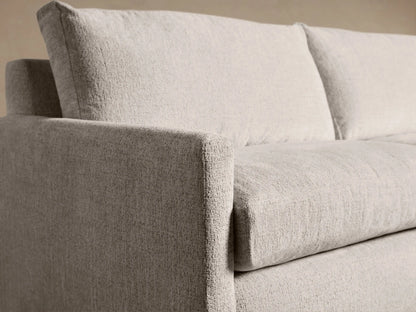 Kipton Slim Arm Sleeper Sofa, light cream textured fabric. Front view on a wooden floor.