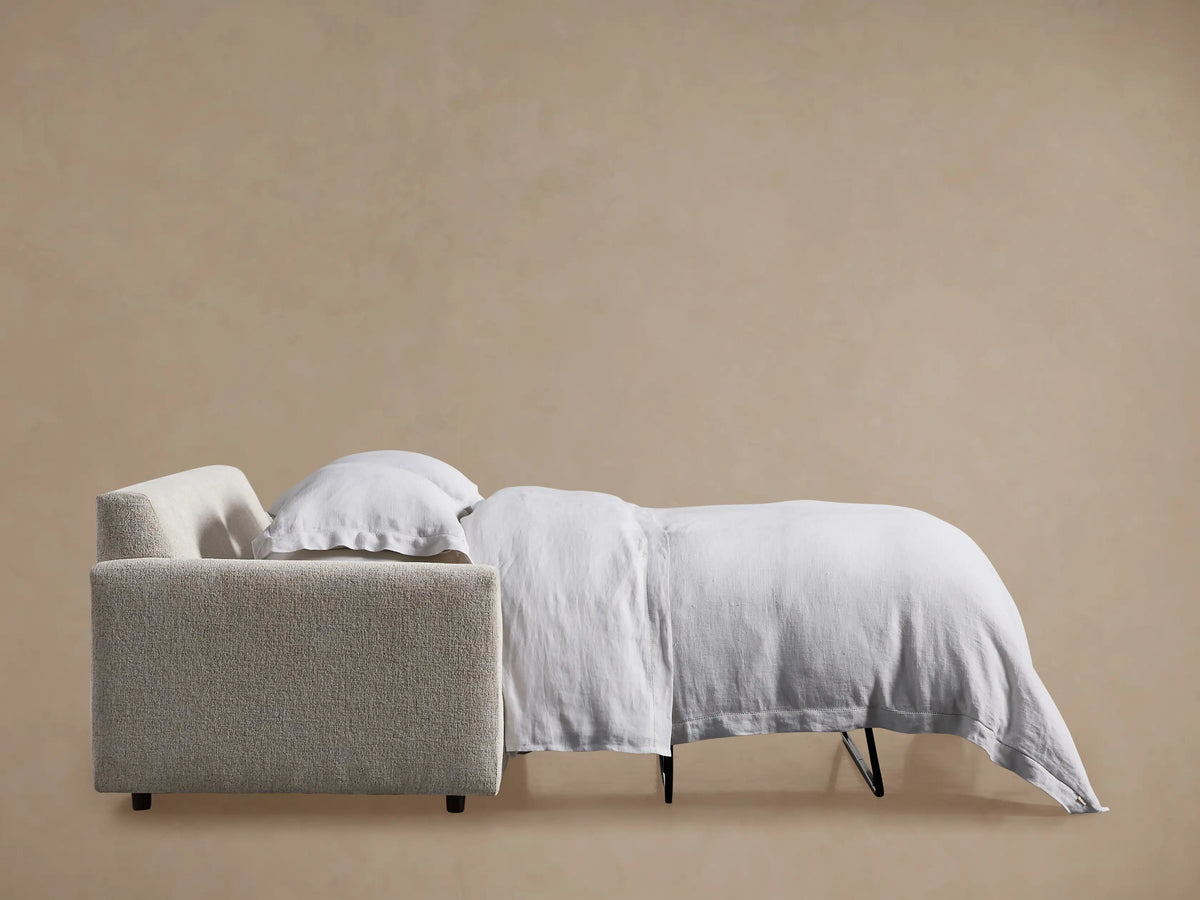 Close-up of a Kipton Slim Arm Sleeper Sofa in a light textured fabric, showing a slim armrest and seat cushions.