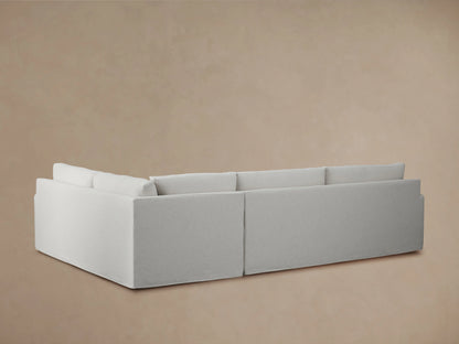 Kipton Slipcovered Two-Piece Sectional in light gray fabric, showing close-up of smooth armrest and plush seat cushions with a soft texture.