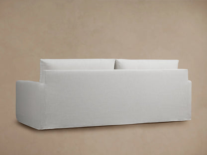 Close-up view of the Kipton Slipcovered Sofa showing its light beige fabric with soft, padded seat and back cushions.