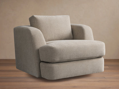 Kayden Swivel Chair with a beige fabric, plush seat, and back cushion. Features subtle rounded armrests and a sturdy swivel base on wooden floor.
