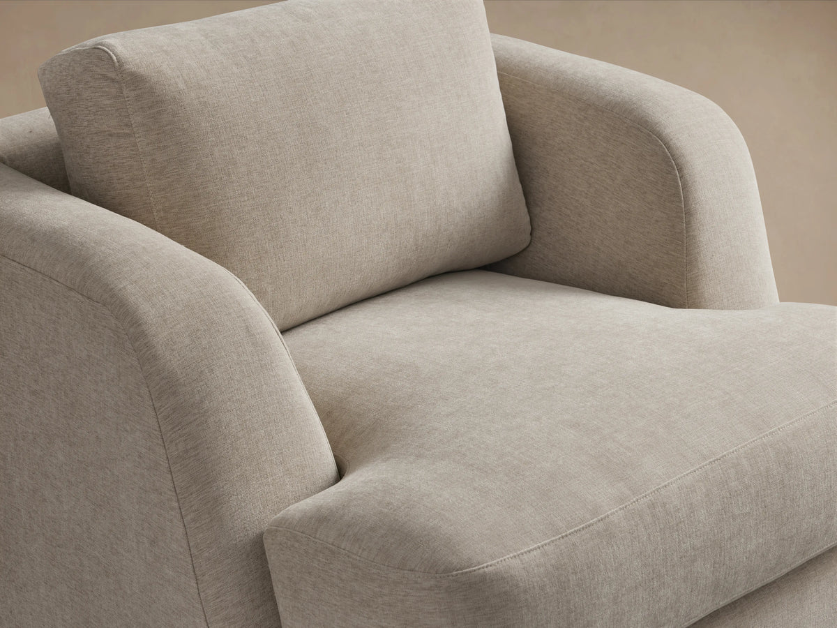 Beige Kayden Swivel Chair with soft upholstery, round arms, cushioned seat and back, set on a hardwood floor.