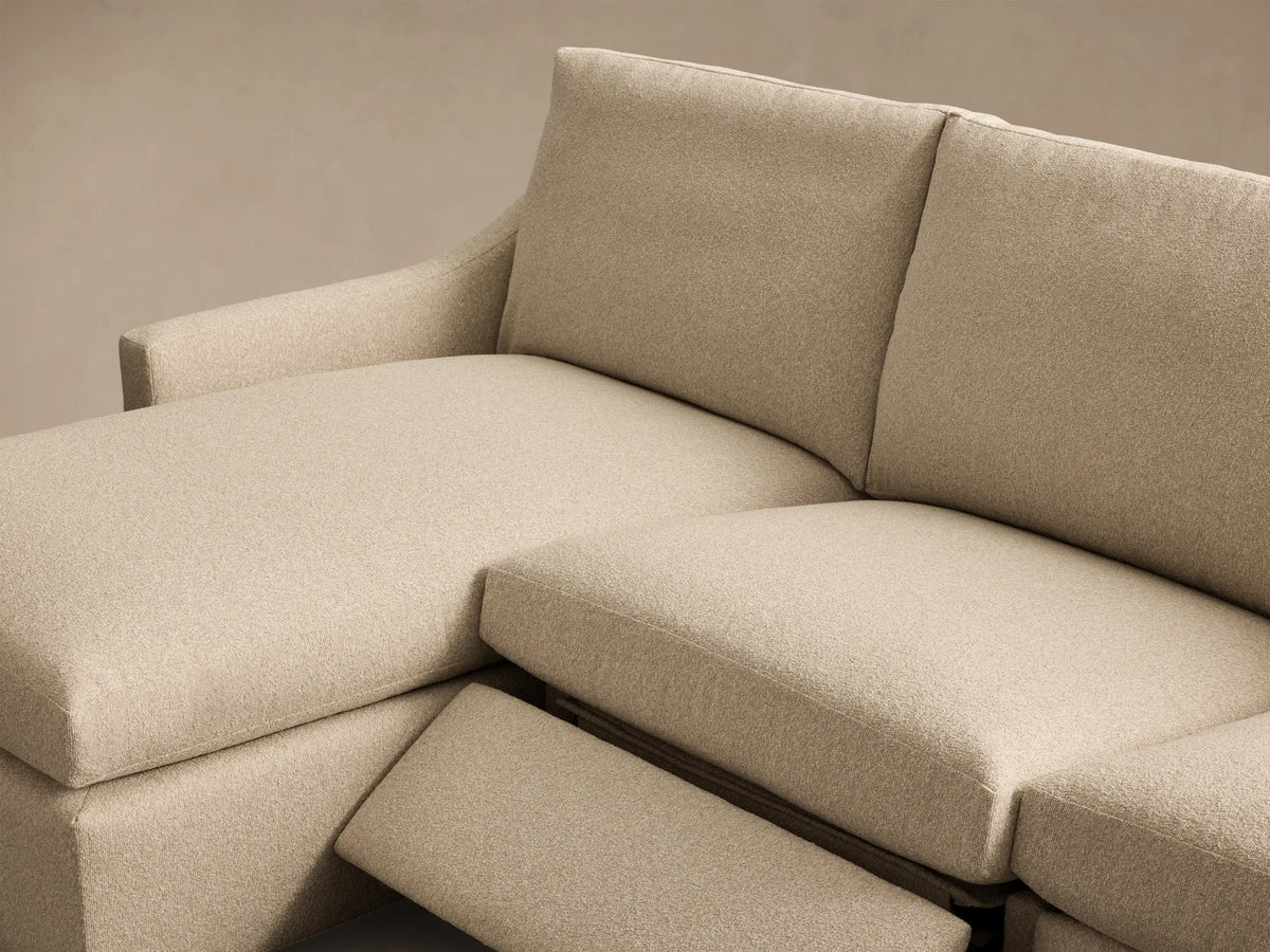 Close-up of the beige textured fabric and silver motion control button on the Kipton Slope Arm Three-Piece Motion Chaise Sectional.