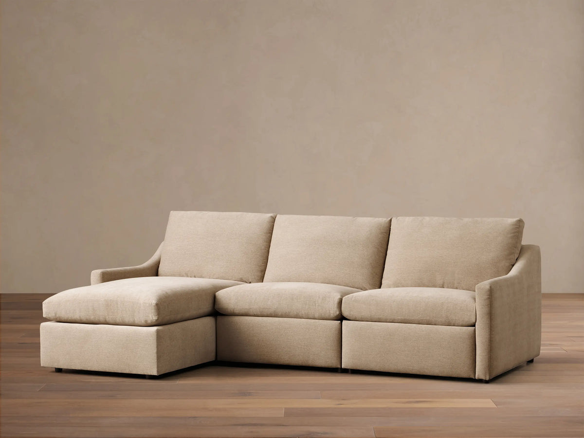 Front view of a light beige Kipton Slope Arm Three-Piece Motion Chaise Sectional™. It features a left-facing chaise and two motion recliners.
