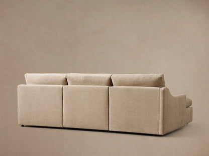 Close-up of a beige Kipton Slope Arm Three-Piece Motion Chaise Sectional, showing the slope arm, a plush seat cushion, and an extended footrest.