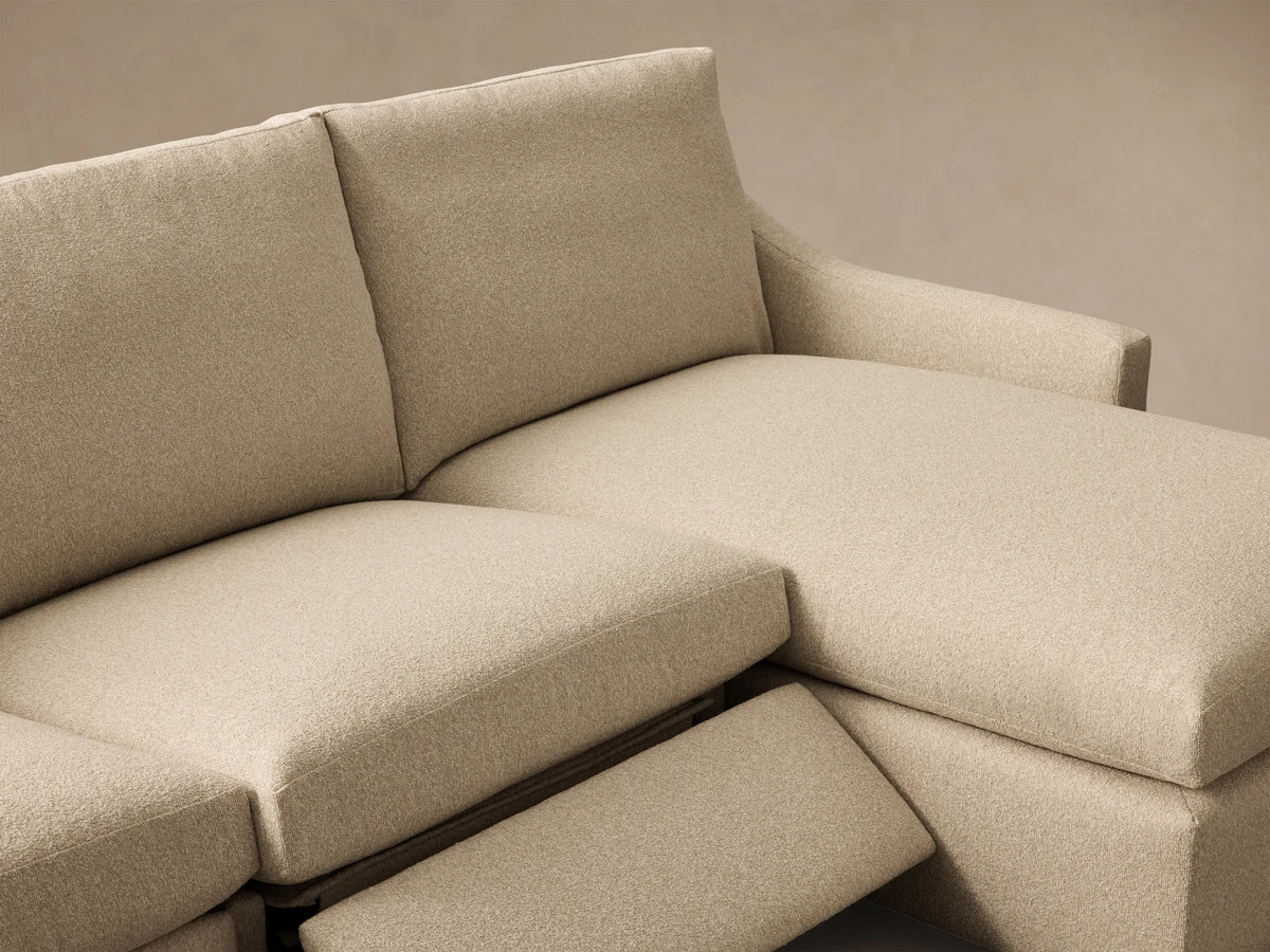 Close-up of the beige Kipton Slope Arm Three-Piece Motion Chaise Sectional with an extended footrest.