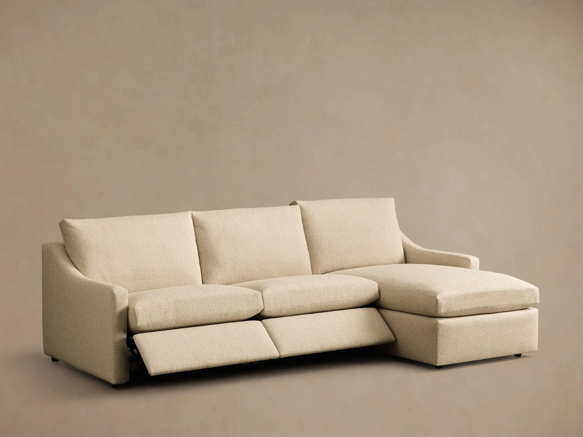 Front view of a light beige Kipton Slope Arm Three-Piece Motion Chaise Sectional with an extended recliner footrest.