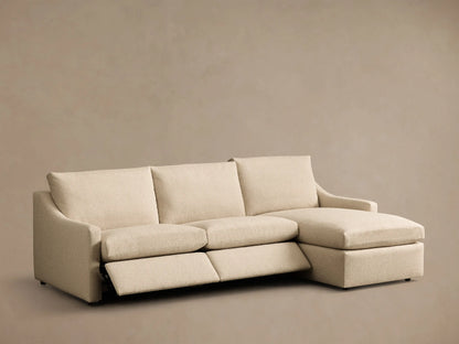 Front view of a light beige Kipton Slope Arm Three-Piece Motion Chaise Sectional with an extended recliner footrest.