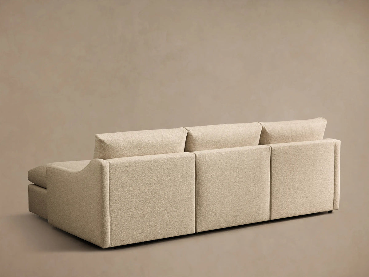 Rear view of the beige Kipton Slope Arm Three-Piece Motion Chaise Sectional, upholstered in textured fabric, showing modular backrests.