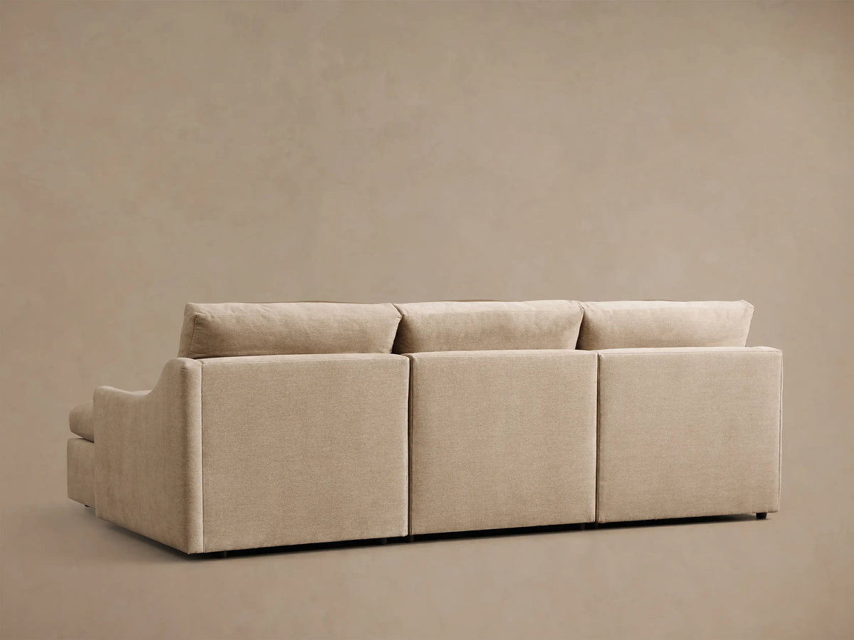 Rear view of the beige Kipton Slope Arm Three-Piece Motion Chaise Sectional, showing three back cushions.