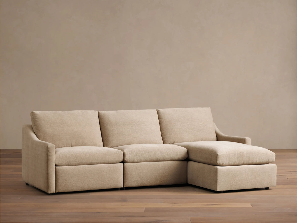 Close-up of the light beige Kipton Slope Arm Three-Piece Motion Chaise Sectional with an oval silver motion control button.