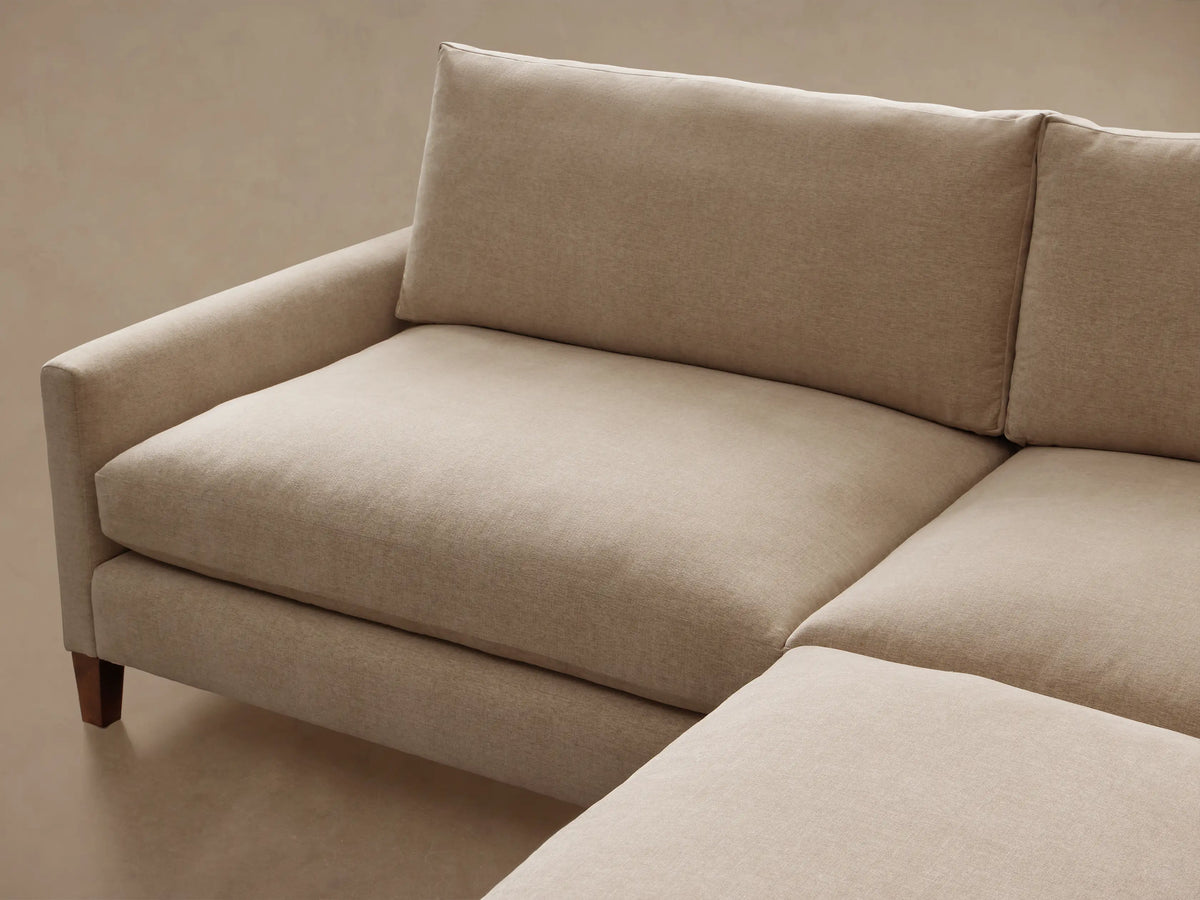 Front view of a light beige Kipton Slim Arm Elevated Two-Piece Sectional with slim arms and mocha-finished feet.