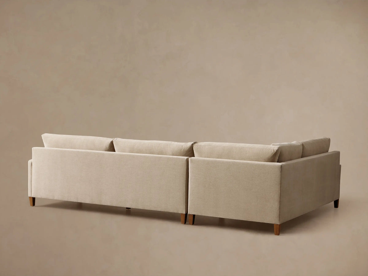 Rear view of a beige Kipton Slim Arm Elevated Two-Piece Sectional with mocha finish feet.