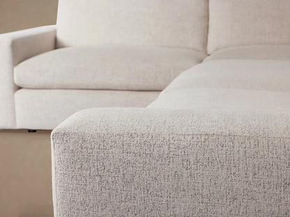 Kipton Wide Arm Two-Piece Sectional, L-shaped, light beige fabric, with wide square arms, on a wooden floor against a beige wall.