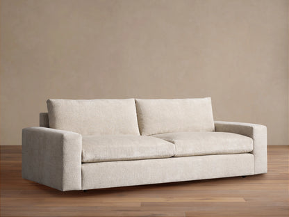 Kipton Wide Arm Sofa in textured cream fabric, with two seat cushions and wide arms, on a wooden floor.