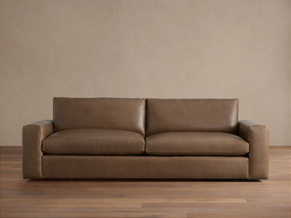 Kipton Wide Arm Leather Sofa, a modern, brown leather 2-seater with wide square arms, two seat cushions, and two back cushions.