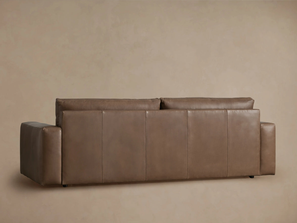 Back view of Kipton Wide Arm Leather Sofa in warm brown. Features clean lines, wide arms, and stitched back panels.