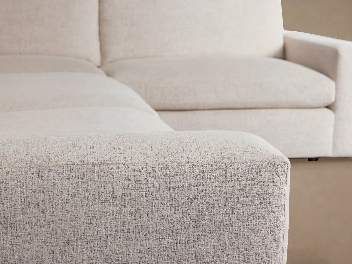 Light beige textured fabric Kipton Wide Arm Two-Piece Sectional, L-shaped, with wide arms, on a wooden floor.