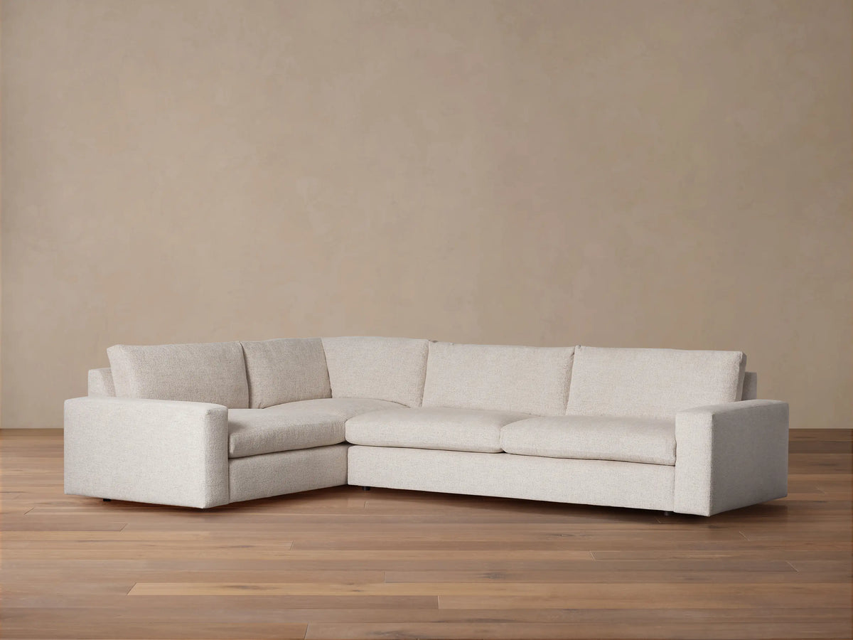 Kipton Wide Arm Two-Piece Sectional, L-shaped, light beige textured fabric, wide arms, plush seat & back cushions, on wood floor.