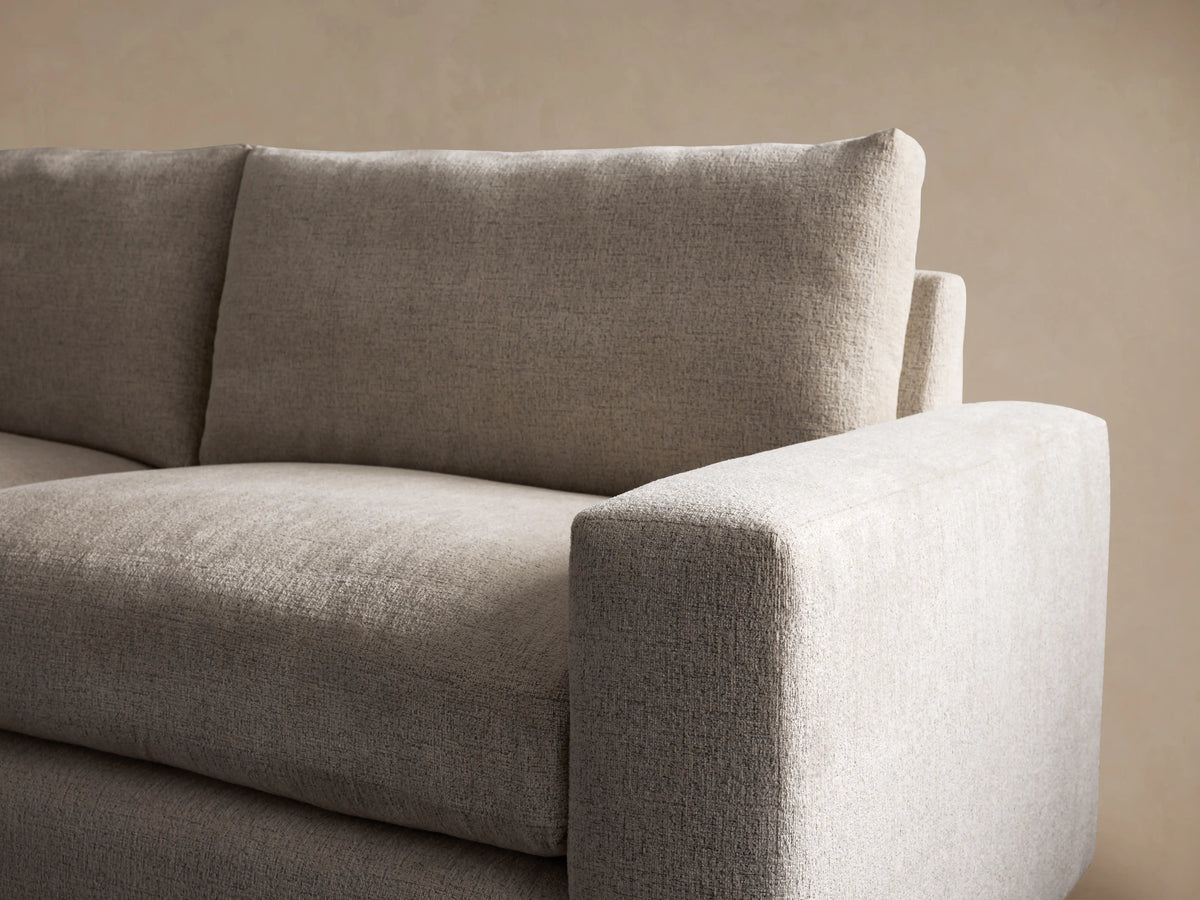 Kipton Wide Arm Sofa, light beige textured fabric, 2-seater with wide block arms, two seat & back cushions, on wood floor.
