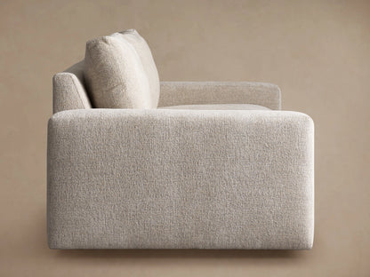 Close-up of a Kipton Wide Arm Sofa in light beige textured fabric, showing a wide arm, back cushion, and seat.