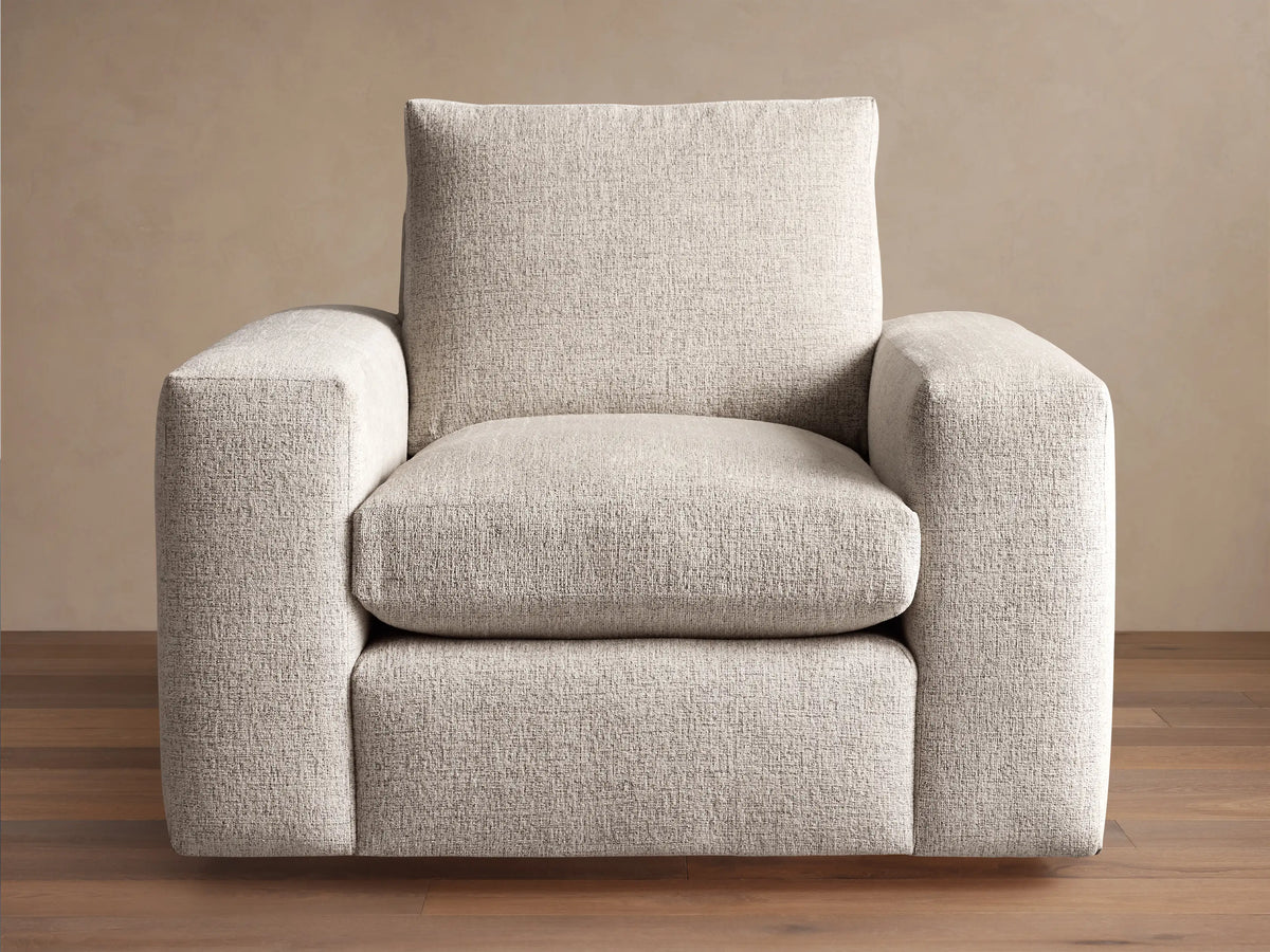 Kipton Wide Arm Swivel Chair. Modern, light beige textured fabric with wide square arms and plush cushions, angled right.