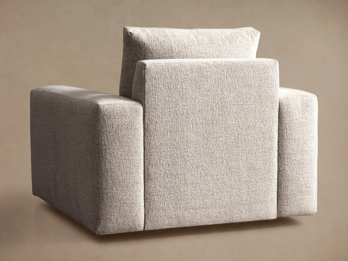Close-up of the Kipton Wide Arm Swivel Chair, featuring light beige textured fabric, wide armrest, seat, and back cushion.